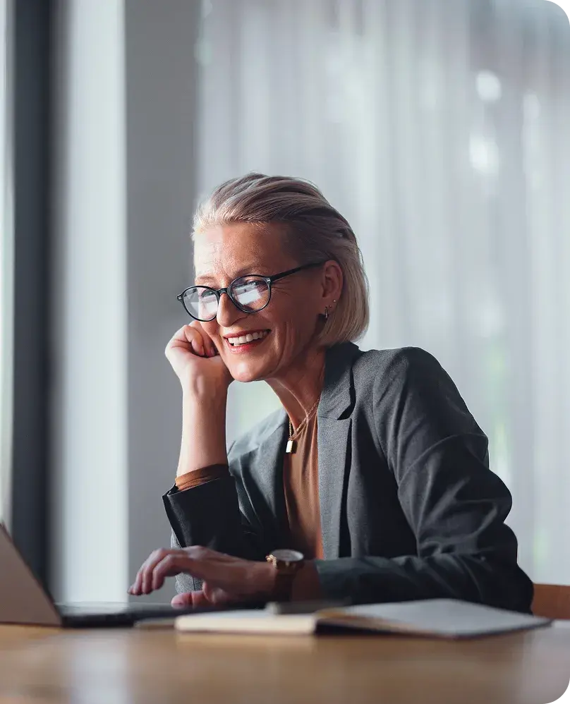woman sitting at a desk with a laptop, and a notebook
